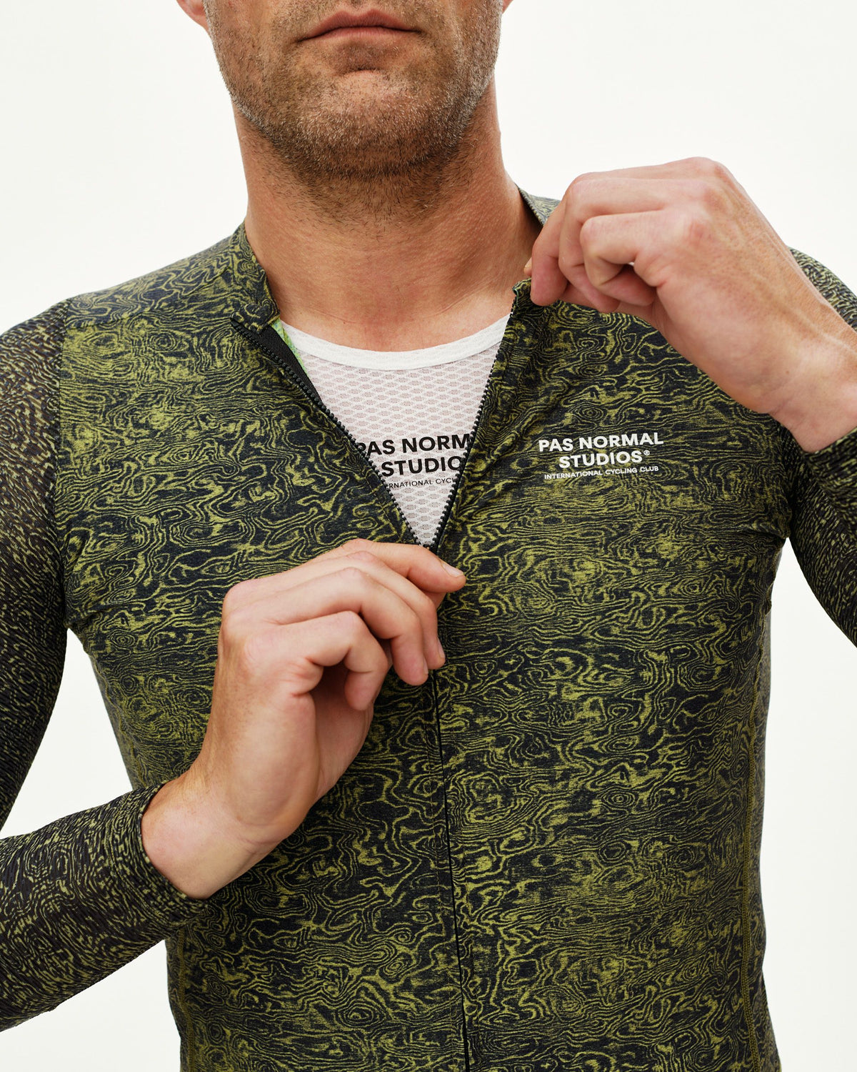 Maillot Largo Pas Normal Studios Essential Light en AOP Grain Dark Lime, detalle sobre ciclista #Color_AOP Grain Dark Lime