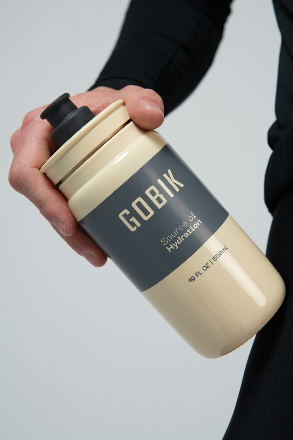 Bidón Gobik Fly en Sand, mano sujetando el bidón beige de perfil #Color_Sand