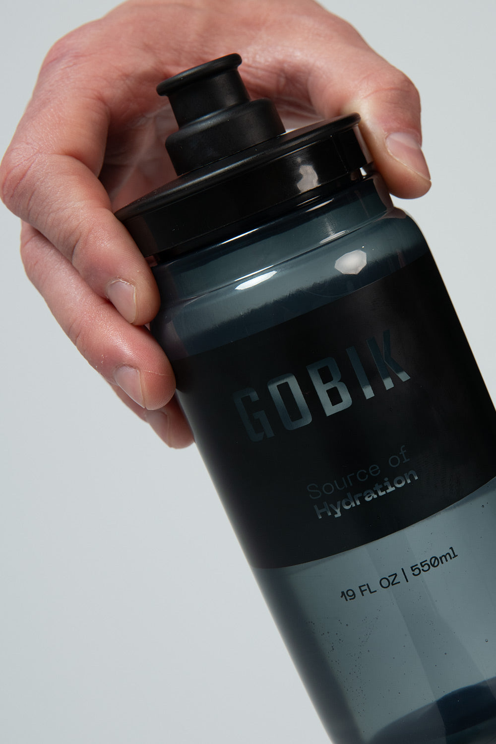 Bidón Gobik Fly en Smoked, mano sujetando el bidón ahumado de 550 cc #Color_Smoked