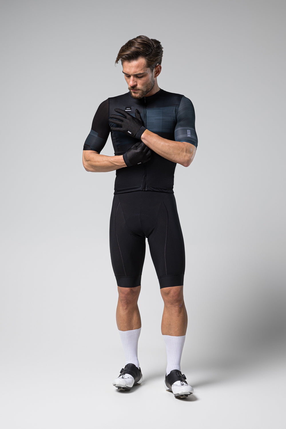 Guantes Gobik Lynx 2.0 en True Black, ciclista de cuerpo entero poniéndose los guantes #Color_True Black