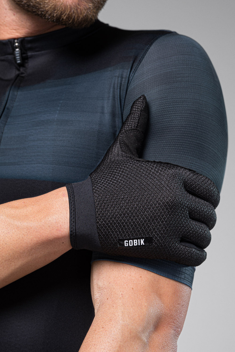 Guantes Gobik Lynx 2.0 en True Black, detalle del dorso del guante y del logotipo del puño sobre modelo #Color_True Black