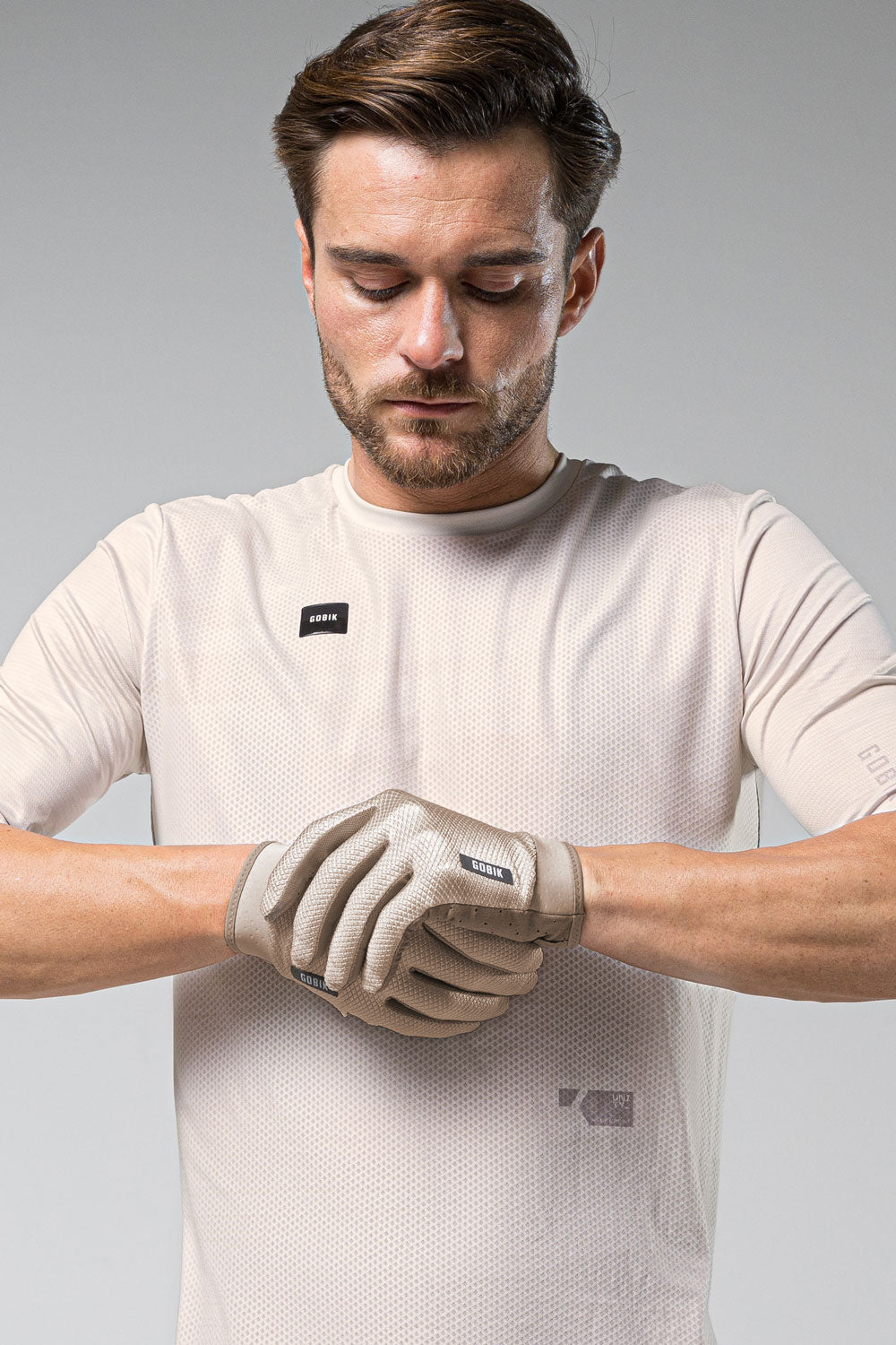 Guantes Gobik Lynx 2.0 en Tofu, modelo ajustándose los guantes sobre camiseta beige #Color_Tofu