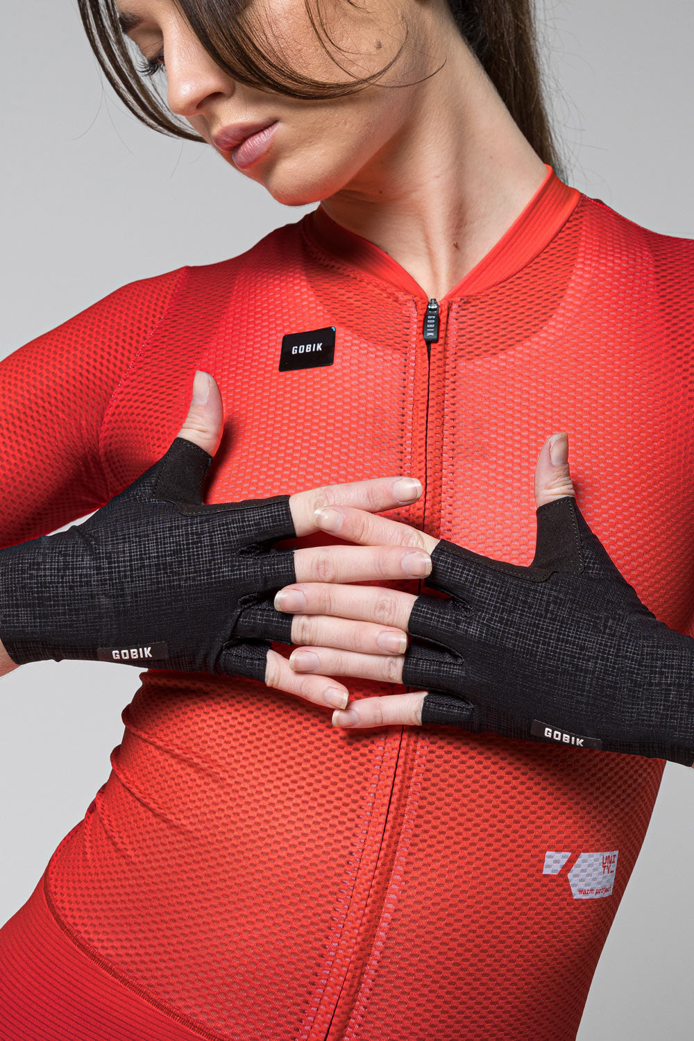 Guantes Gobik Mamba 2.0 en Black, guantes puestos sobre ciclista con maillot rojo, manos cruzadas #Color_Black