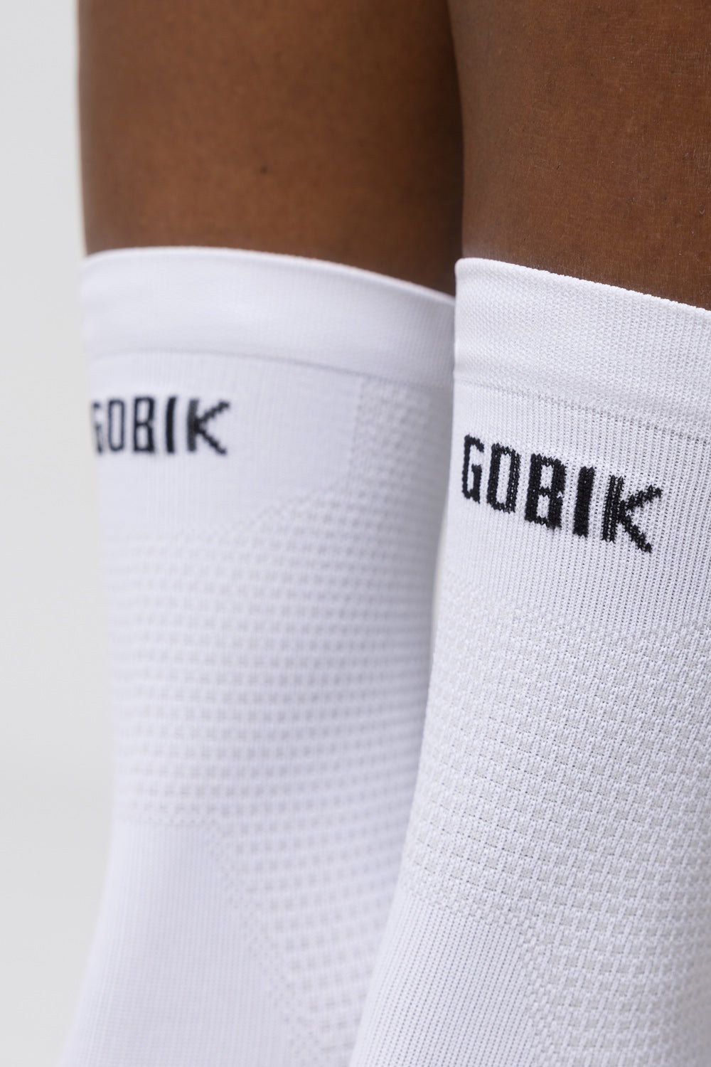 Calcetines Gobik Lightweight 2.0 en Salt, detalle de las cañas blancas con el logotipo Gobik sobre el modelo #Color_Salt