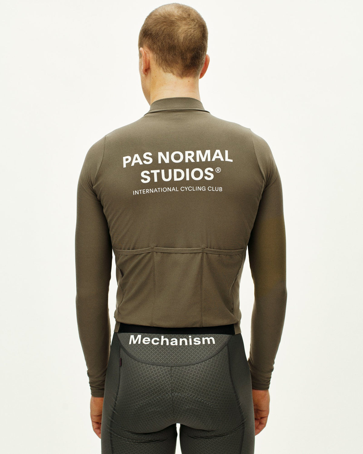 Maillot Largo Pas Normal Studios Mechanism en Mud, vista trasera sobre ciclista #Color_Mud