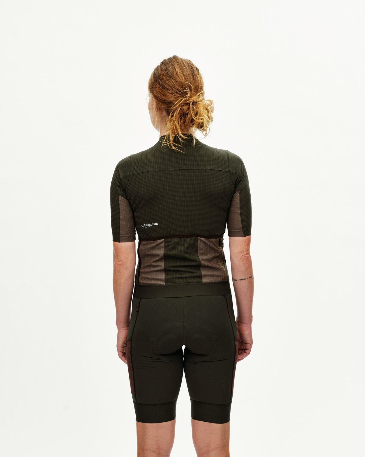 Maillot corto de mujer Pas Normal Studios Escapism en Dark Olive, de espaldas sobre la ciclista #Color_Dark Olive