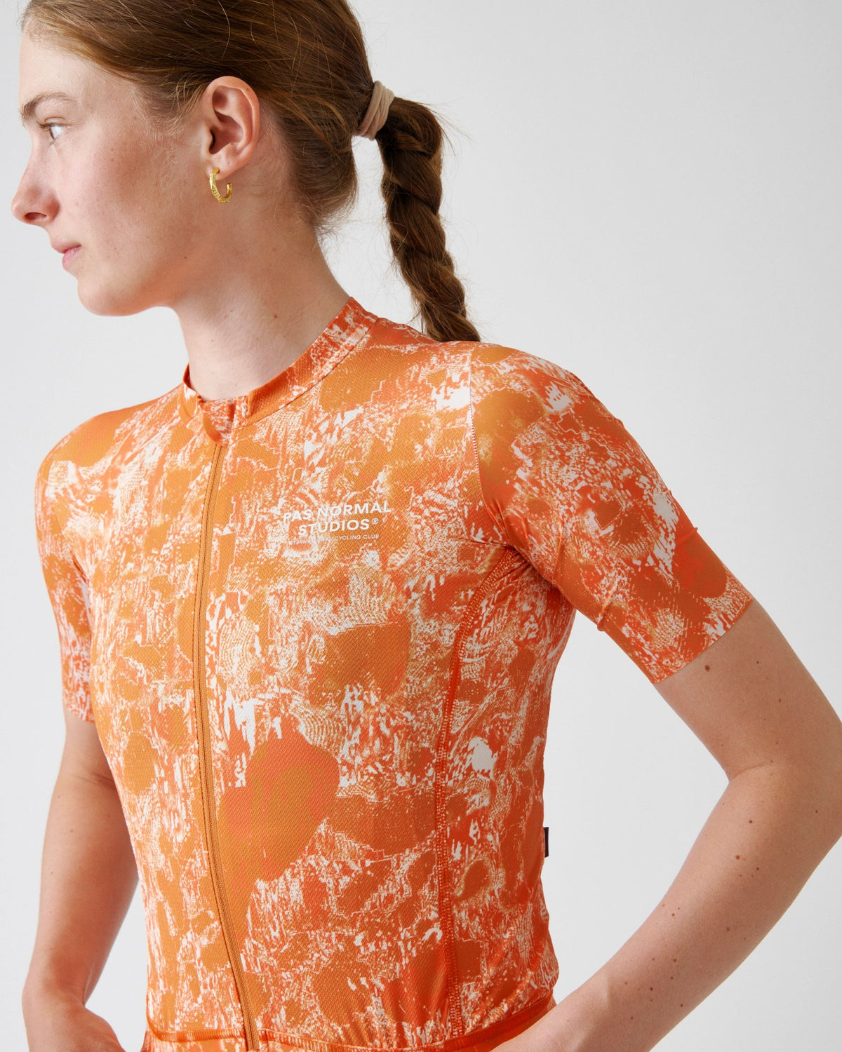 Maillot Mujer Pas Normal Studios Solitude Late Drop en Orange, sobre ciclista #Color_Orange
