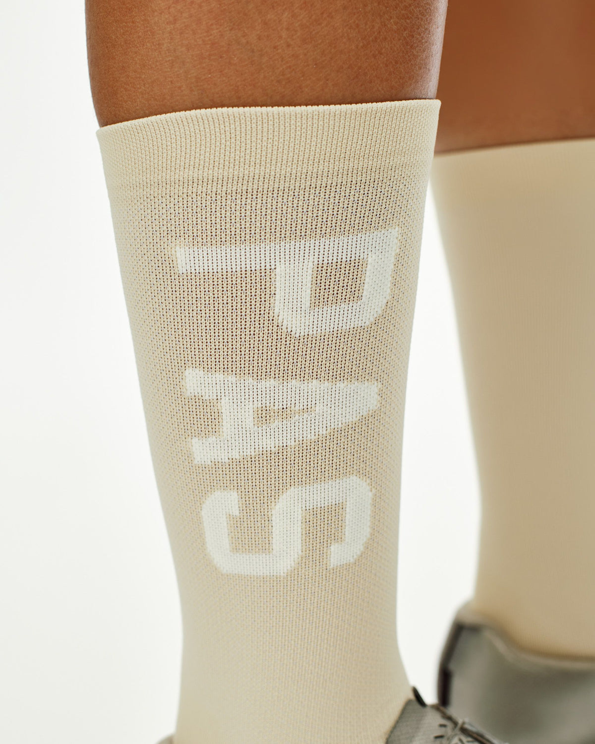 Cream PAS cycling socks on model with white logo knit pattern #Color_Cream