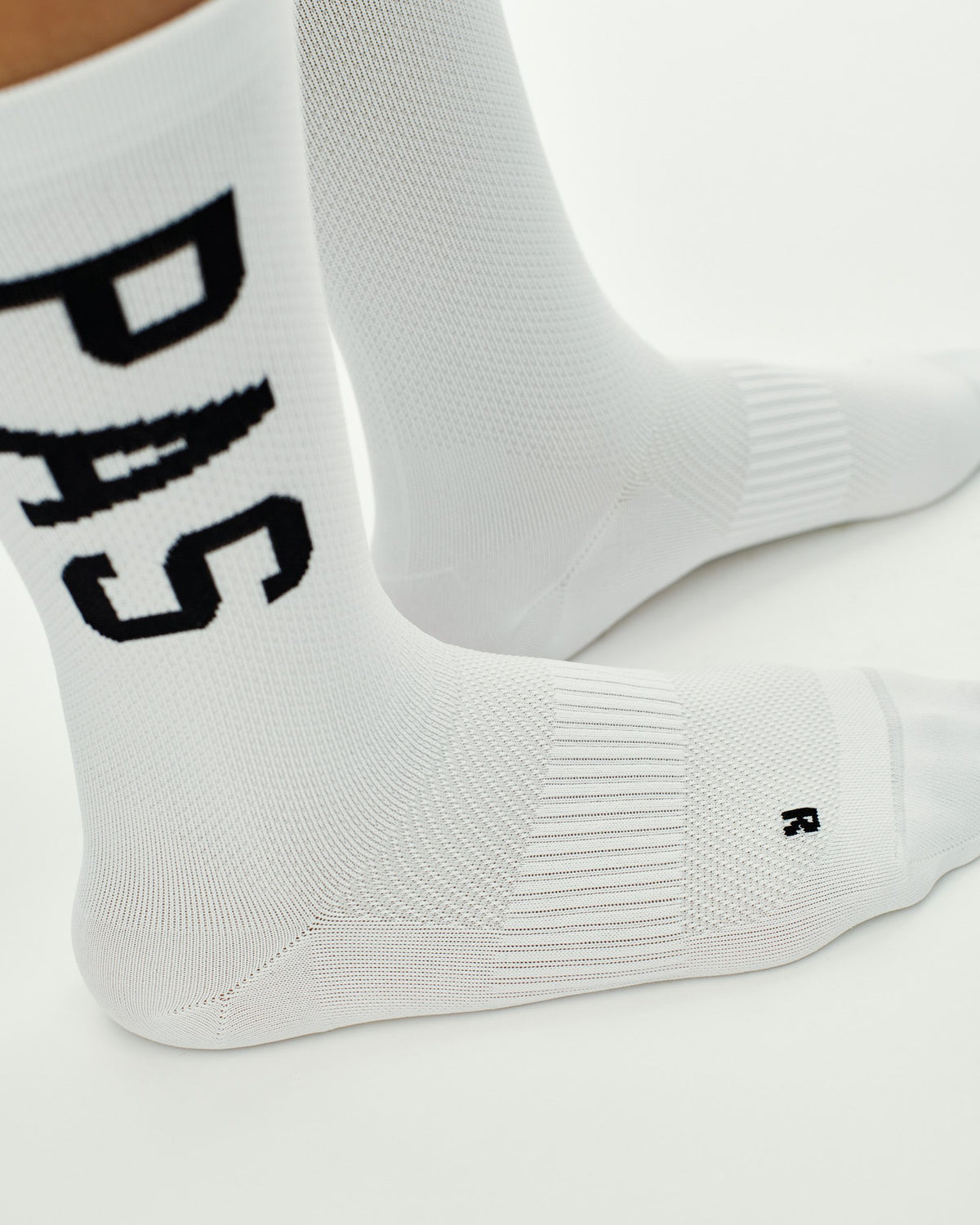 White PAS cycling socks with black logo lettering and textured sole panel #Color_White