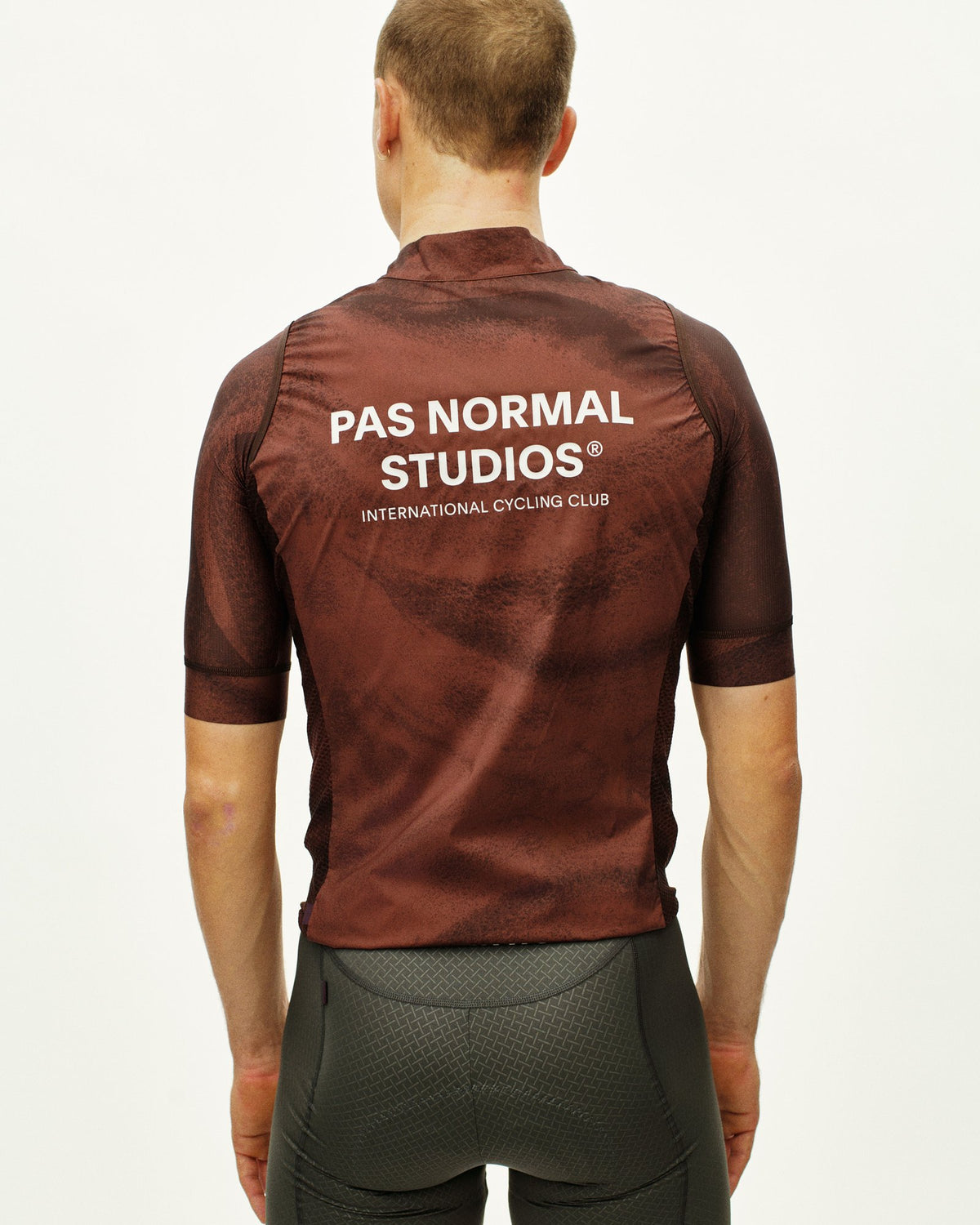 Chaleco Pas Normal Studios Mechanism Stow Away en AOP Light Brown, sobre modelo, vista trasera #Color_AOP Light Brown