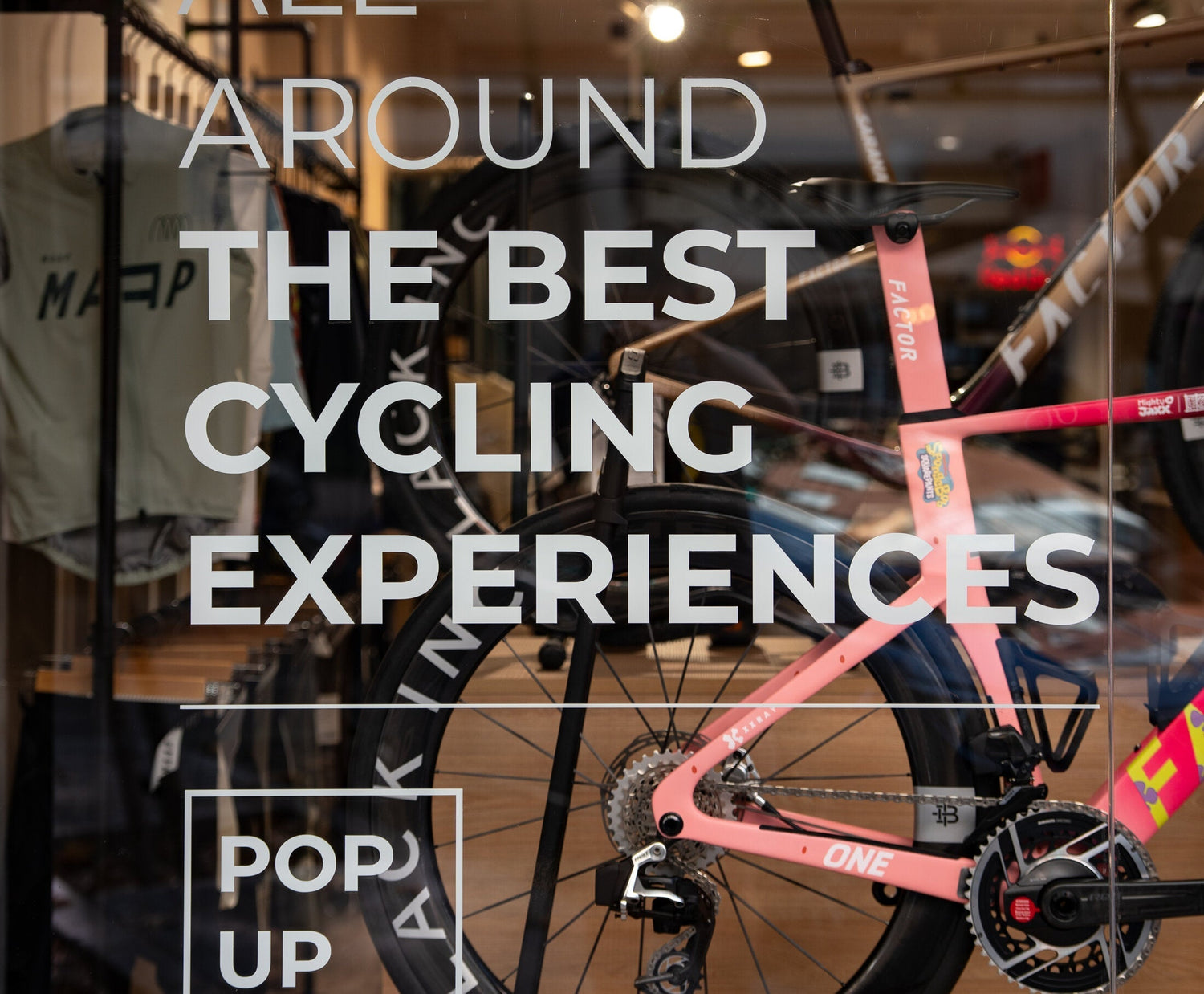 Escaparate del pop-up de Dog Days en Edgar Neville 37, con una bicicleta Factor rosa y el mensaje All around the best cycling experiences