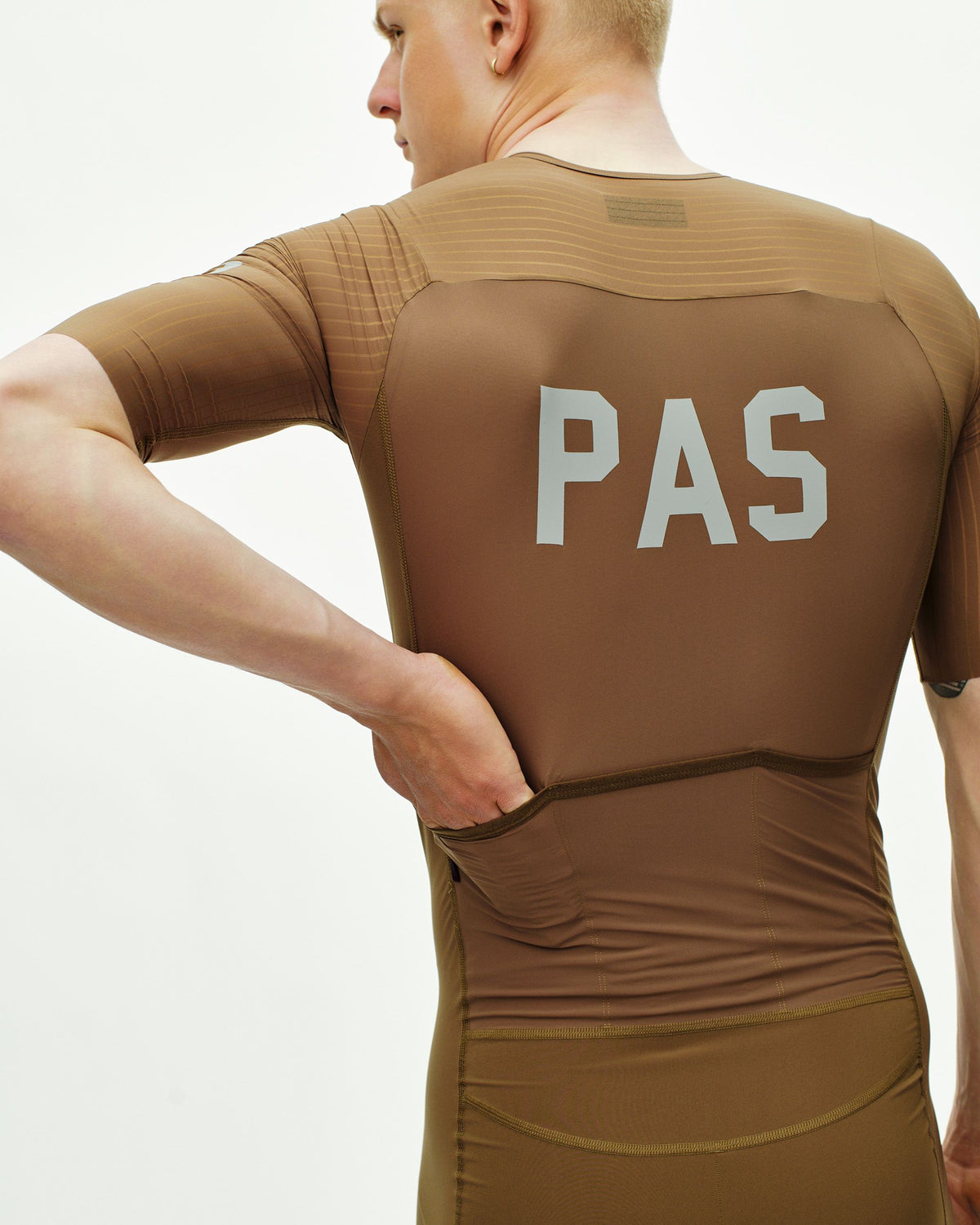 Brown PAS Mechanism Pro speedsuit on model, rear view with white chest logo #Color_Brown