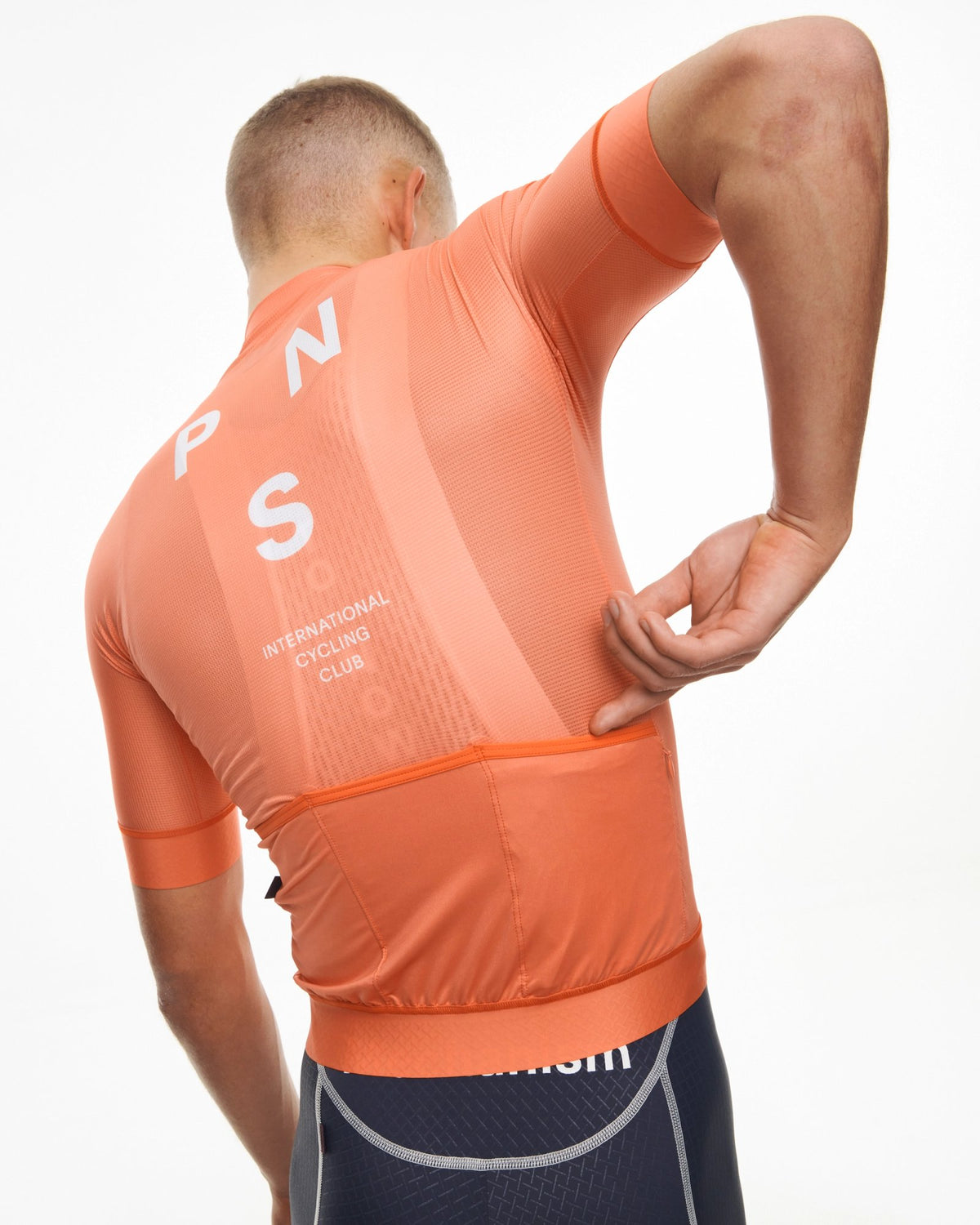 Maillot Corto Pas Normal Studios Mechanism en Coral, vista trasera sobre ciclista #Color_Coral