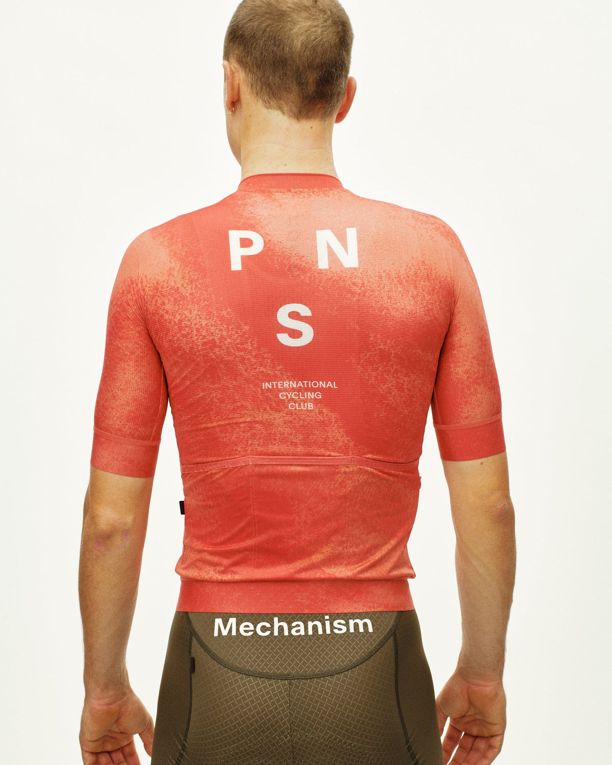 Maillot Corto Pas Normal Studios Mechanism en AOP Hibiscus Orange, vista trasera sobre ciclista #Color_AOP Hibiscus Orange
