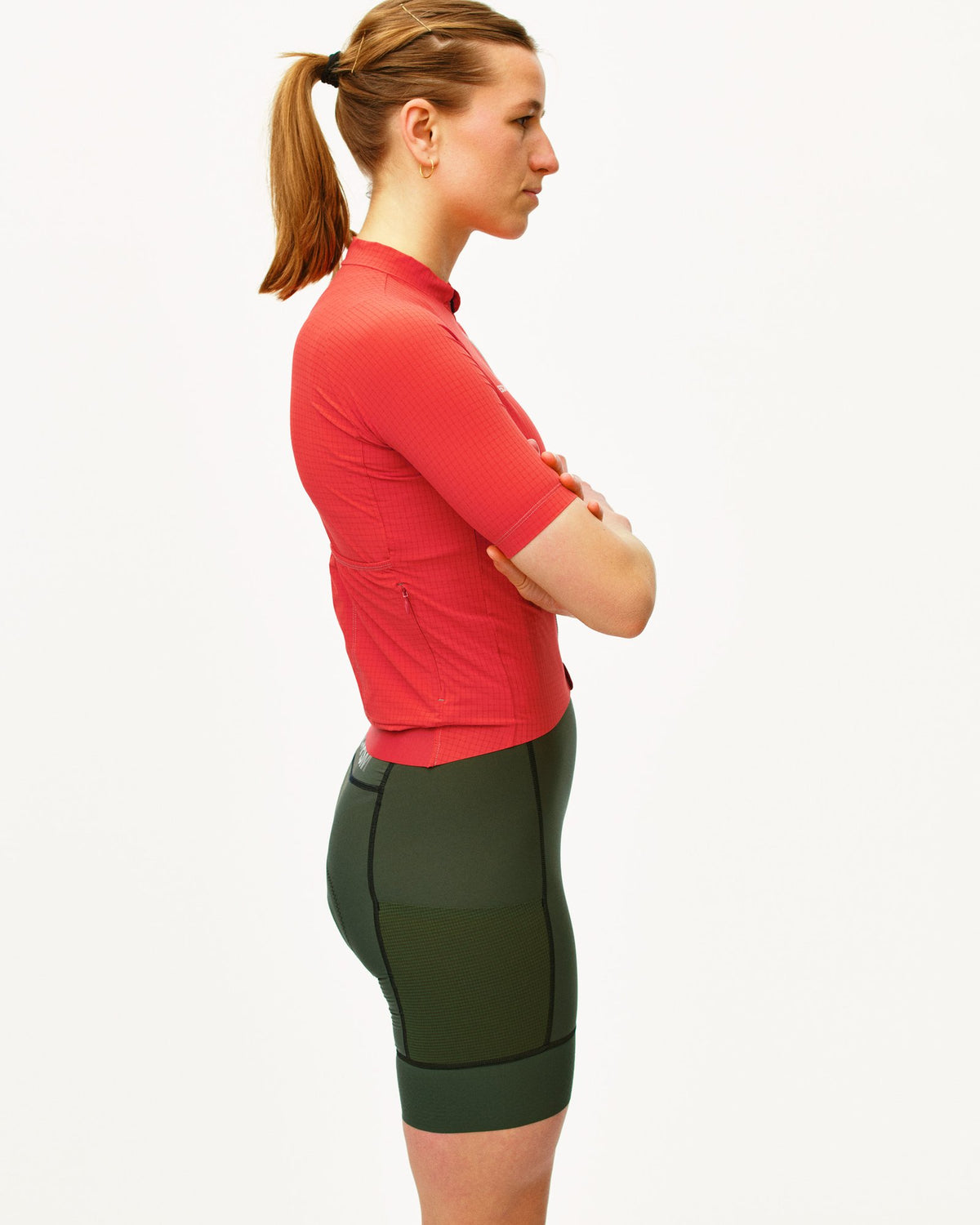 Maillot corto de mujer Pas Normal Studios Escapism Light en Classic Red, de perfil sobre la ciclista #Color_Classic Red