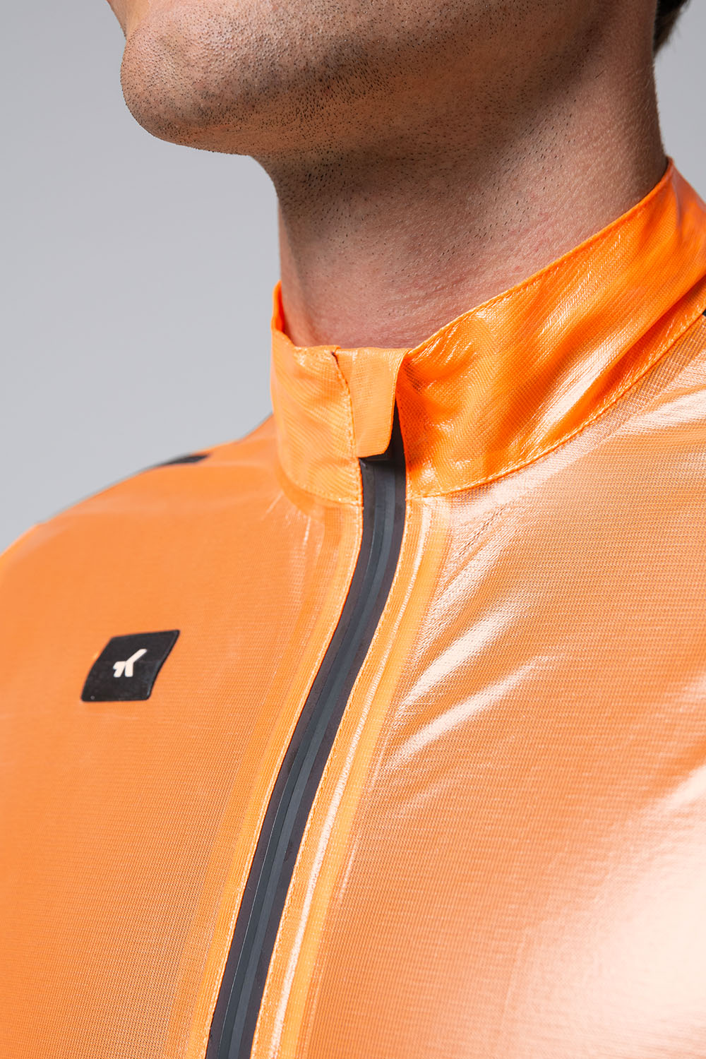 Chaqueta Gobik Pluvia 2.0 en Blazing Orange, detalle del cuello, la cremallera sellada y el logotipo #Color_Blazing Orange