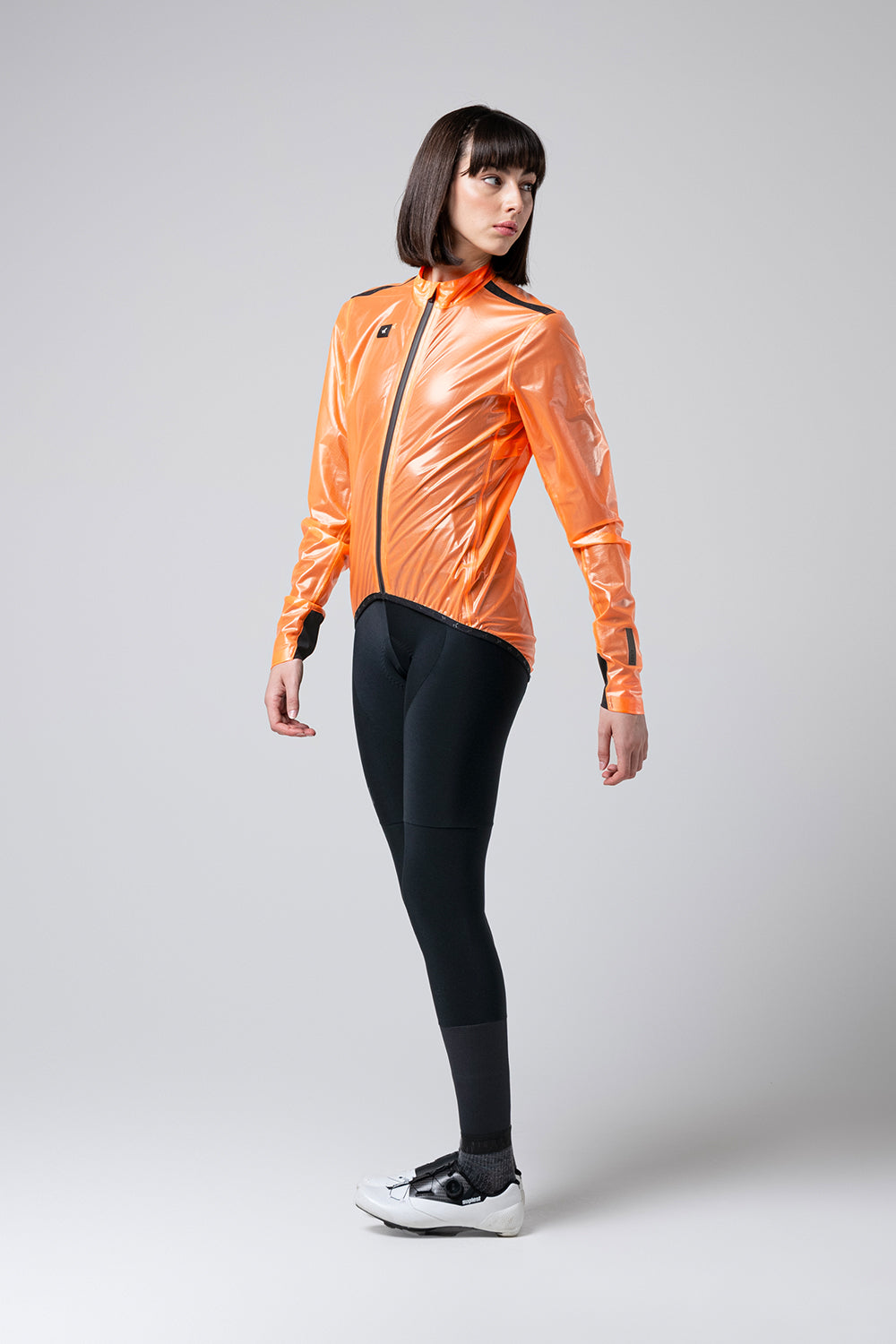 Chaqueta Gobik Pluvia 2.0 en Blazing Orange, vista de tres cuartos de cuerpo entero sobre modelo femenino #Color_Blazing Orange
