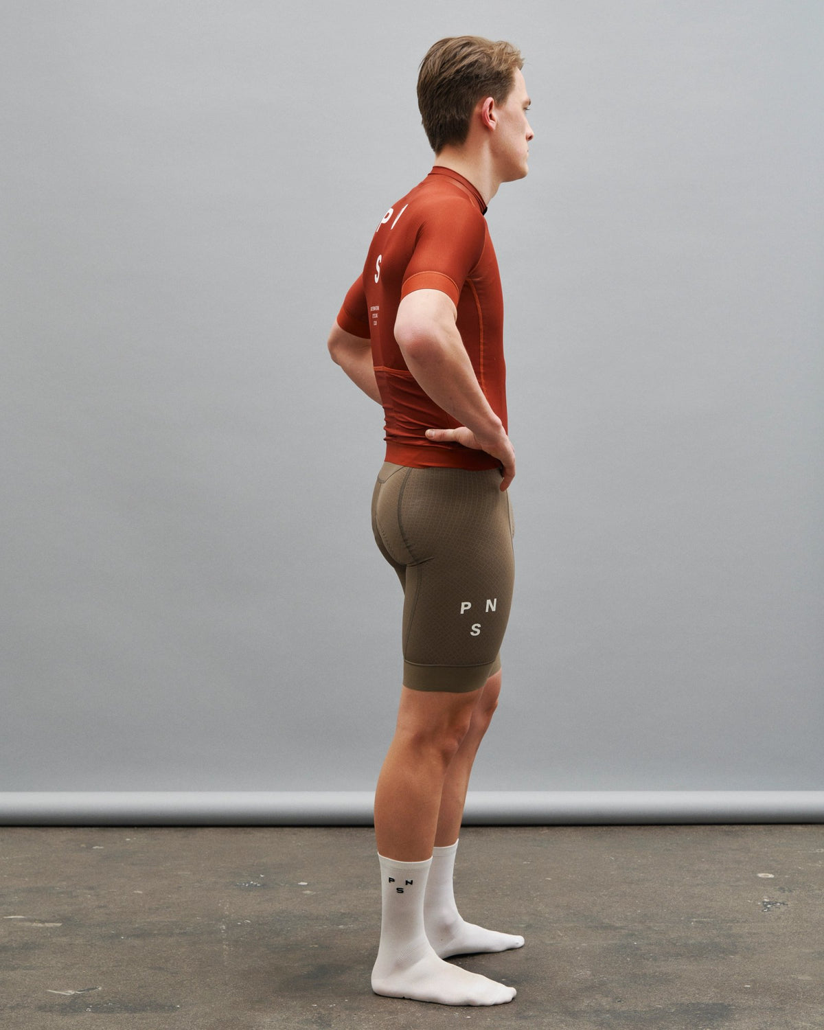 Maillot Corto Pas Normal Studios Mechanism en Brick, vista lateral sobre ciclista #Color_Brick