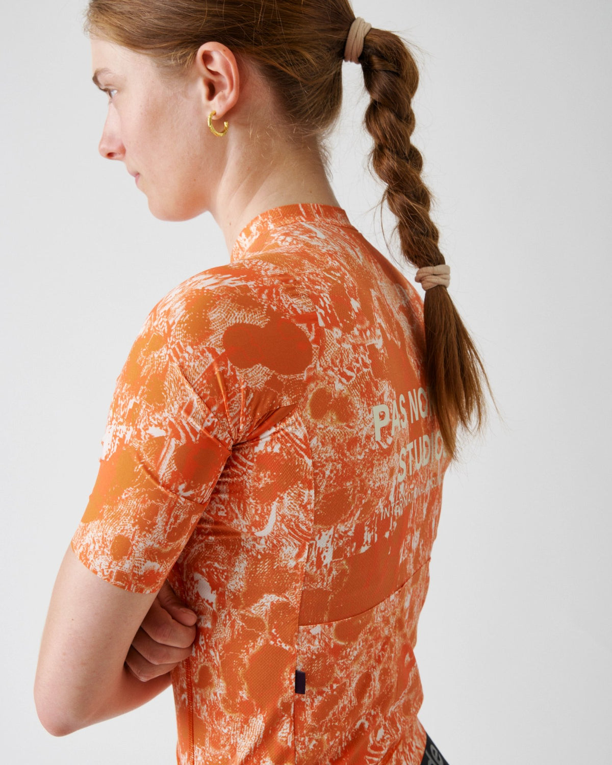 Maillot Mujer Pas Normal Studios Solitude Late Drop en Orange, sobre ciclista, vista trasera #Color_Orange