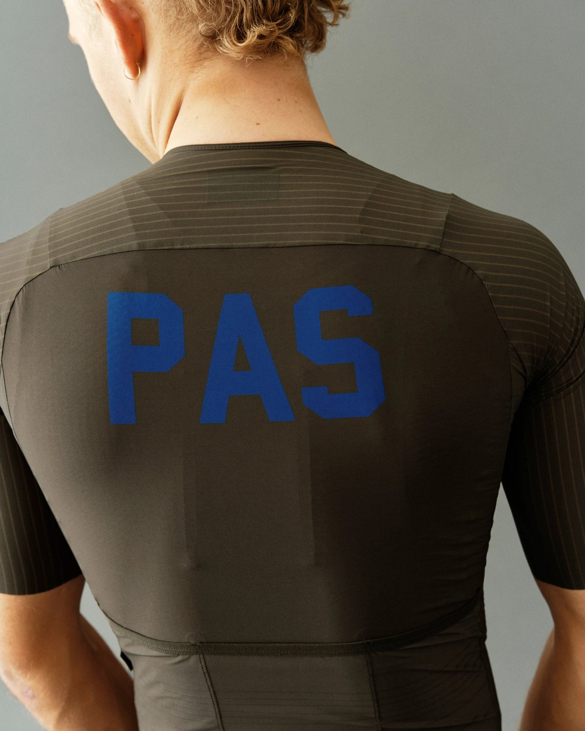 Maillot corto Pas Normal Studios PAS Mechanism Pro en Dark Olive, de espaldas sobre el ciclista #Color_Dark Olive