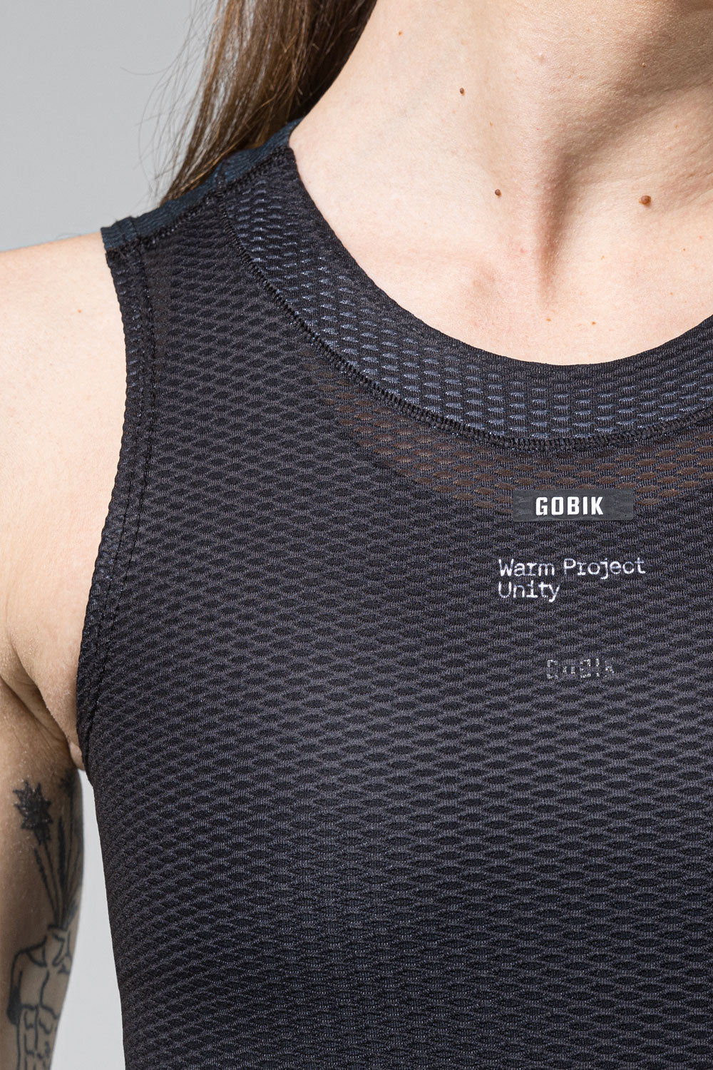 Camiseta Interior Mujer Gobik Second Skin en Moonless, detalle frontal del cuello con el logotipo Gobik y la etiqueta Warm Project Unity #Color_Moonless