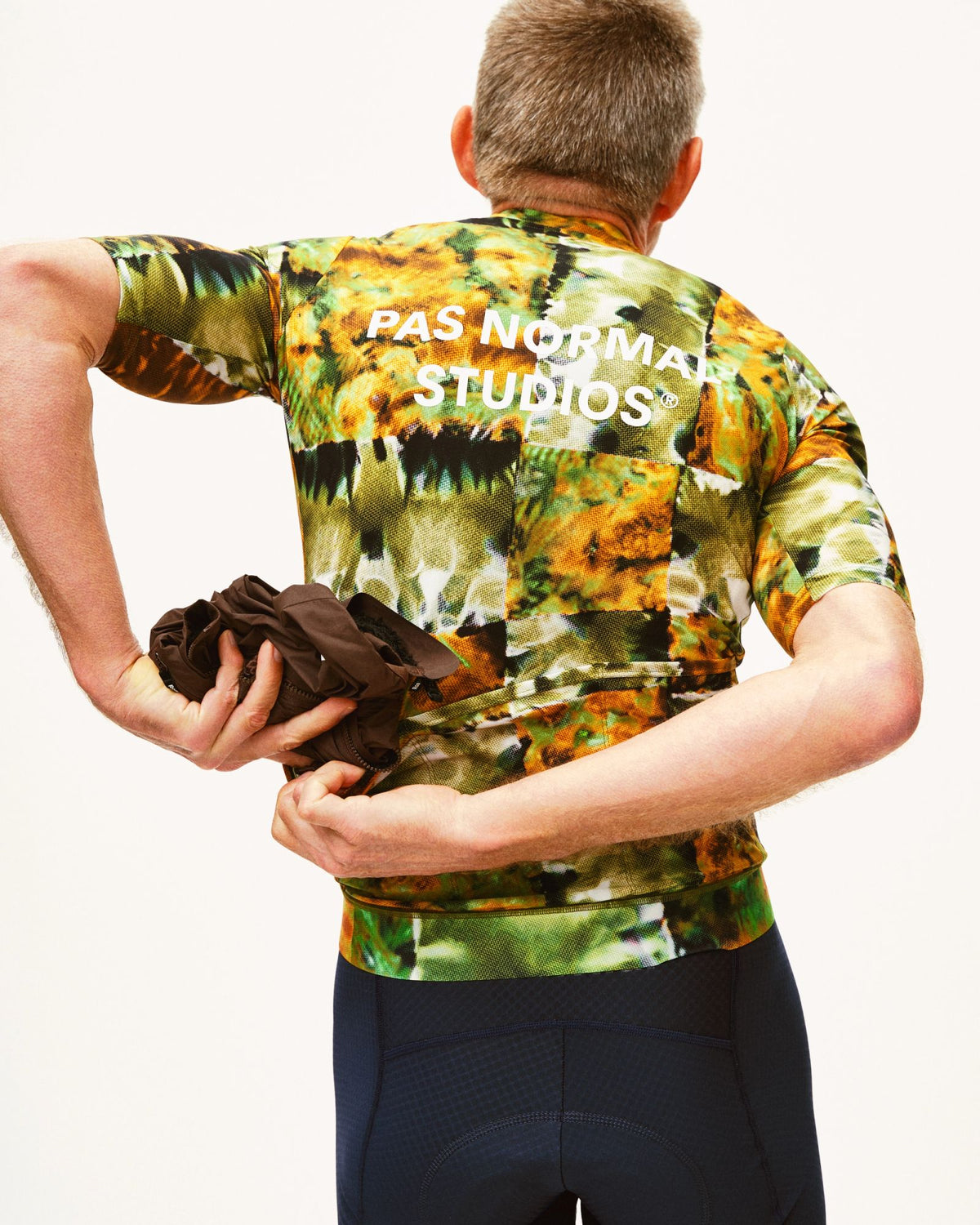 Maillot Corto Pas Normal Studios Essential en Kaleidoscope Green, vista trasera sobre ciclista #Color_Kaleidoscope Green