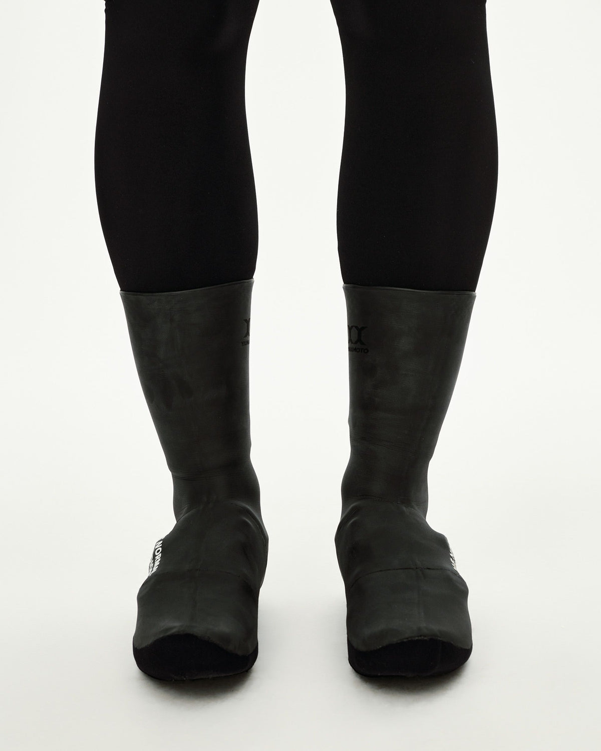 Black Logo Heavy cycling overshoes, front view on model as a pair with white logo print at toe #Color_Black