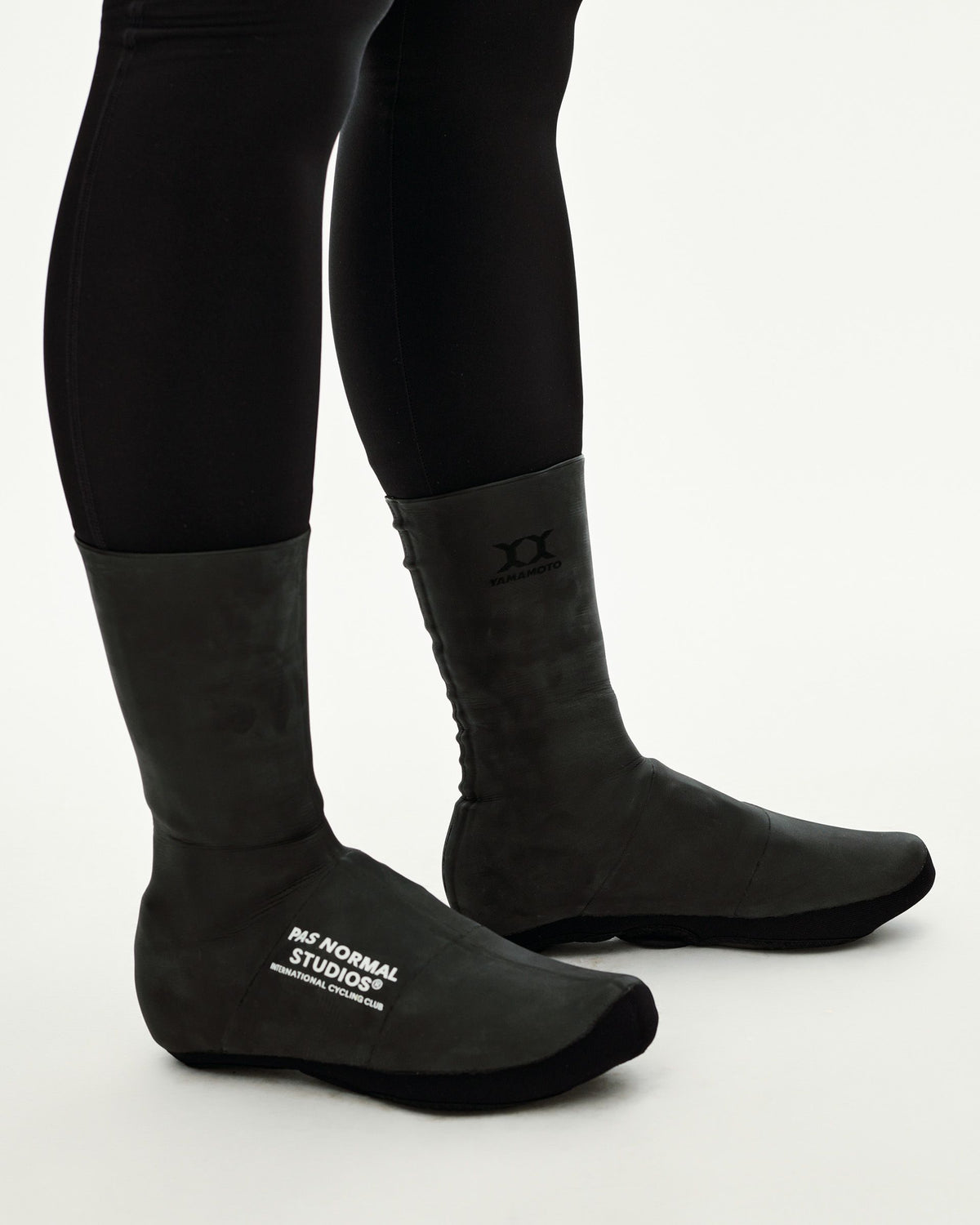 Black Logo Heavy cycling overshoes on model, side view with white chest logo print and Yamamoto branding #Color_Black