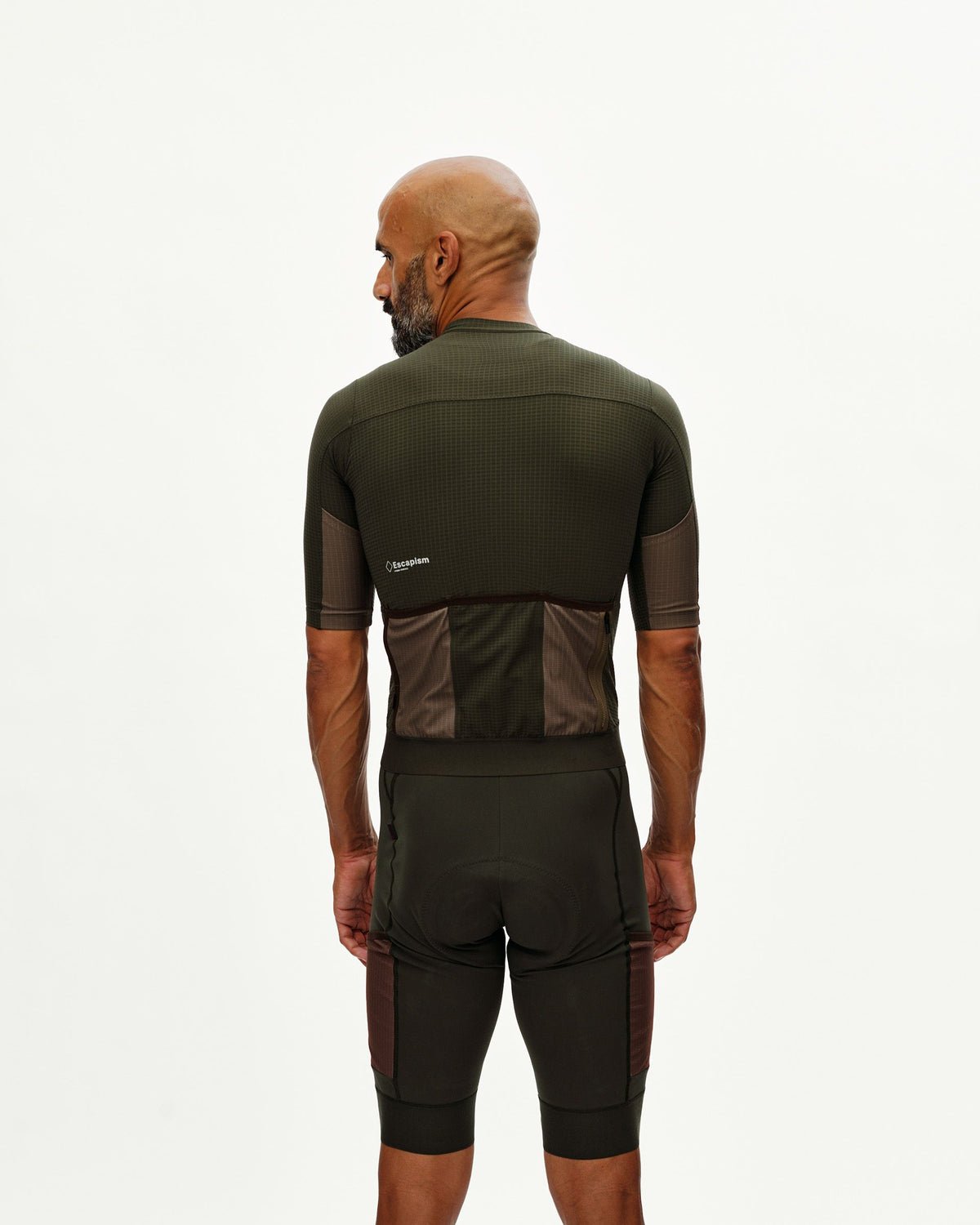 Maillot Corto Pas Normal Studios Escapism en Dark Olive, vista trasera sobre ciclista #Color_Dark Olive