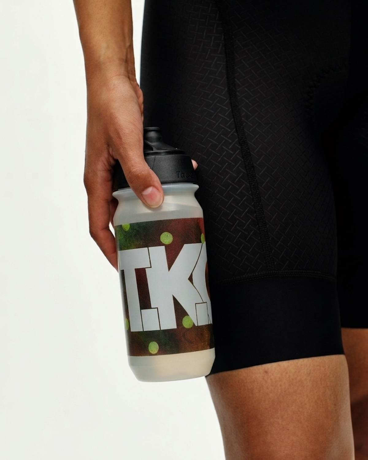Brown T.K.O. bidon held in hand with camouflage print and white logo #Color_T.K.O. Brown