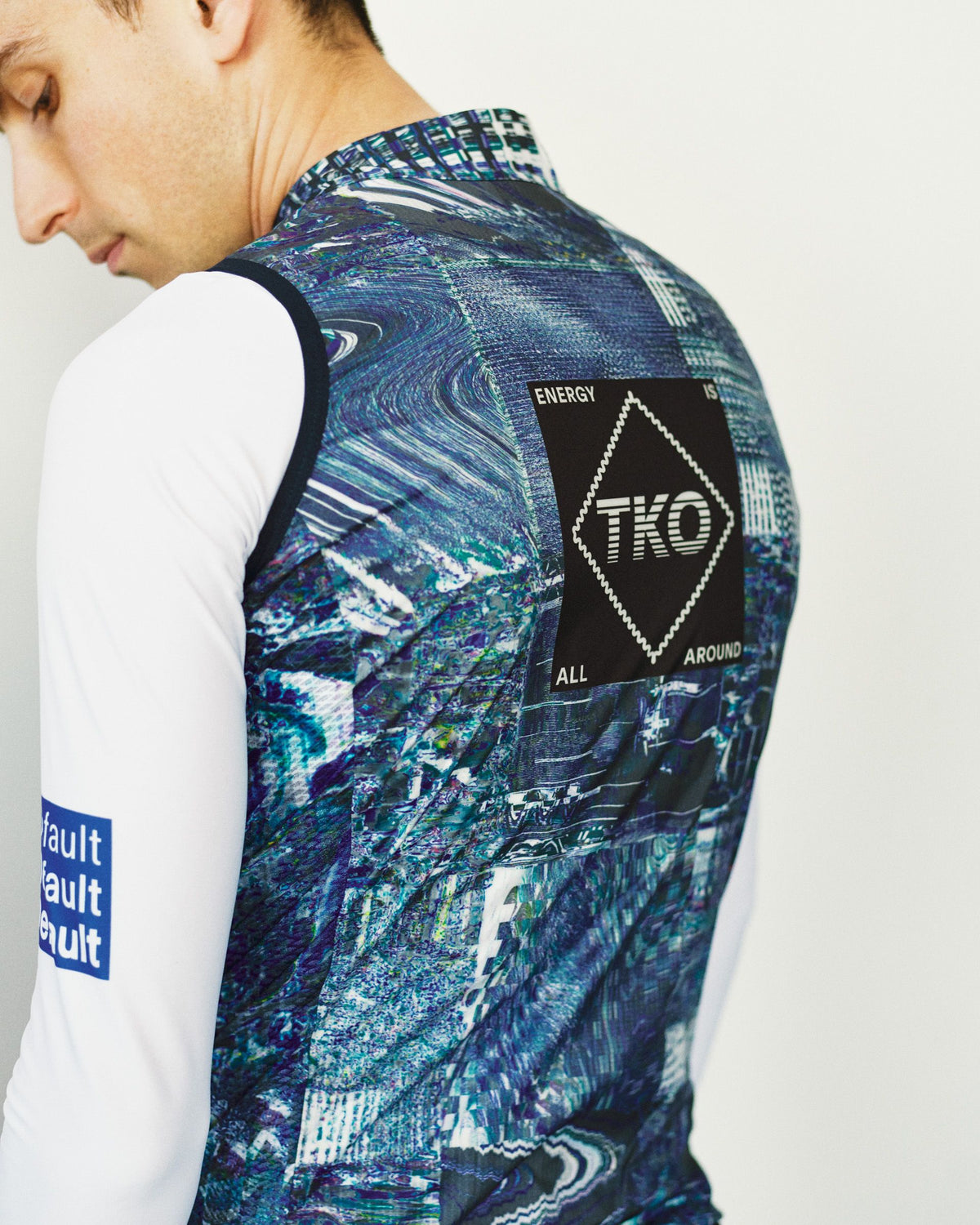 Human Error Blue T.K.O. Mechanism Stow Away cycling gilet, rear view on model with abstract print and TKO back patch #Color_Human Error Blue