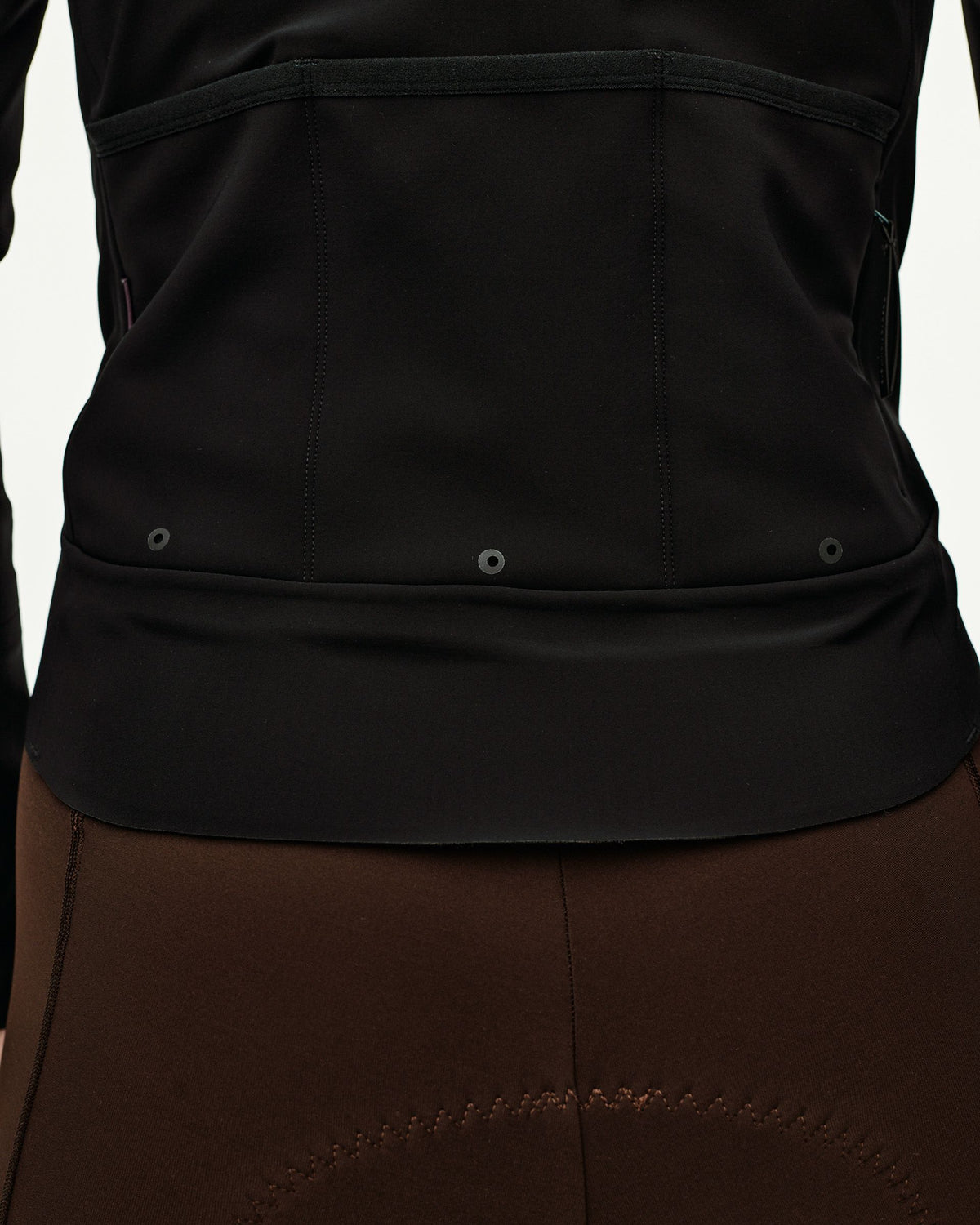 Black Mechanism women's thermal cycling jacket, rear detail on model showing back pockets and elasticated hem #Color_Black