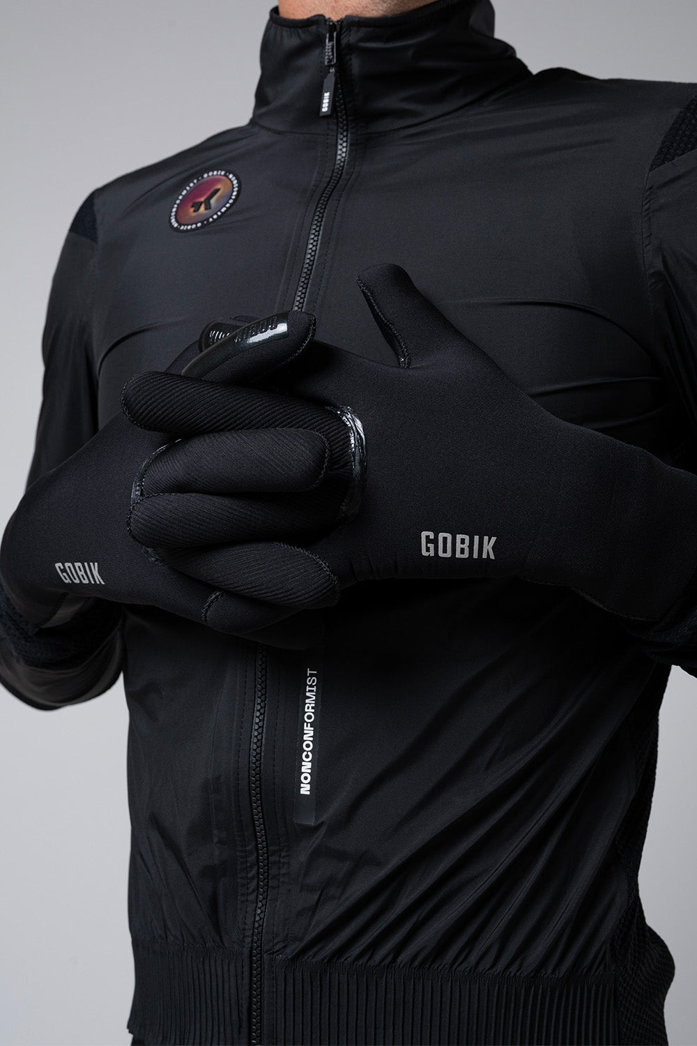 Guantes Gobik Tundra 3.0 en Black, detalle de las manos con los guantes puestos sobre la chaqueta negra #Color_Black