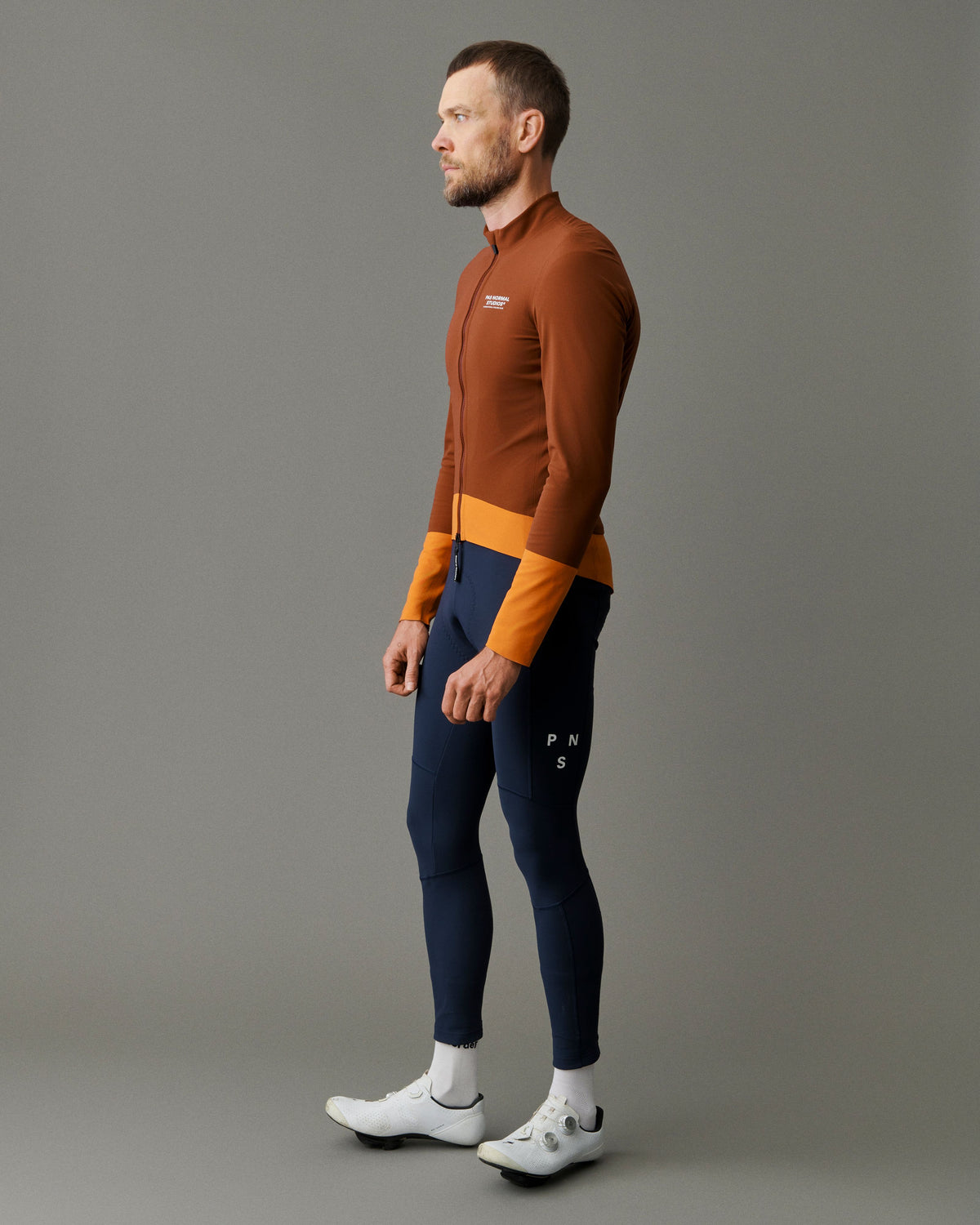 Brown Mechanism Thermal cycling jacket on model, side view with orange color-block panels #Color_Mahogany / Dark Orange