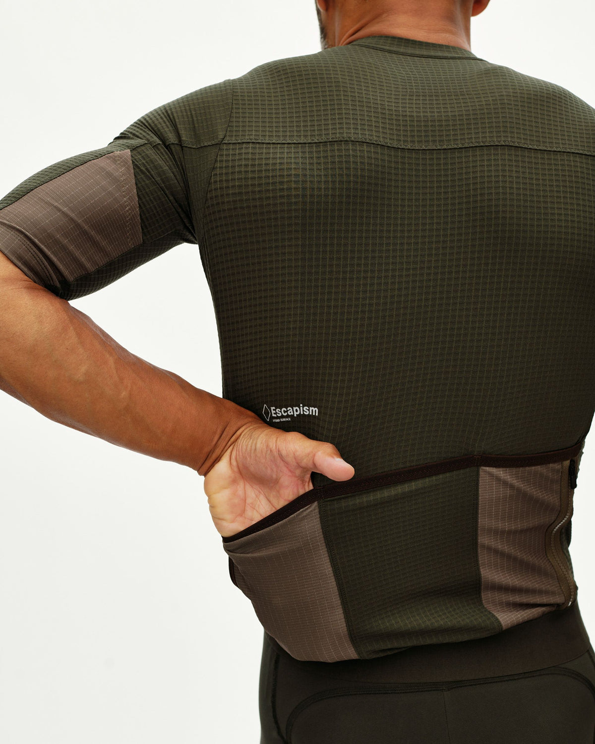 Maillot Corto Pas Normal Studios Escapism en Dark Olive, detalle trasero sobre ciclista #Color_Dark Olive