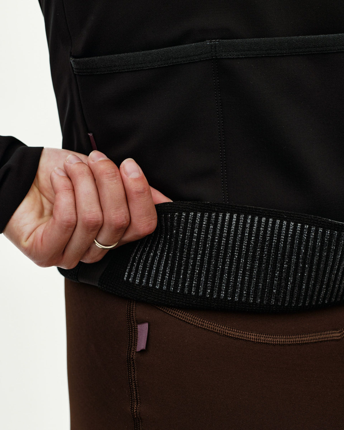 Black Mechanism Thermal cycling jacket, detail view on model showing ribbed gripper hem band #Color_Black