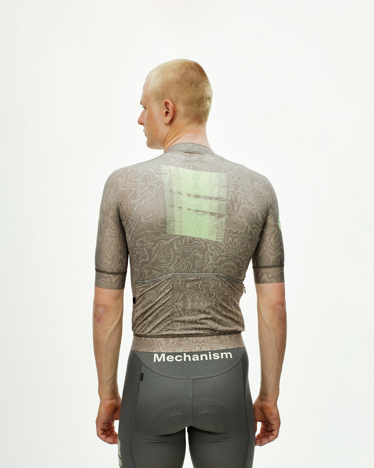 Maillot Corto Pas Normal Studios Mechanism Logo en AOP RTN Earth, vista trasera sobre ciclista #Color_AOP RTN Earth