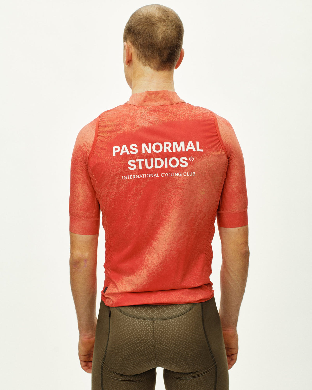 Chaleco Pas Normal Studios Mechanism Stow Away en AOP Hibiscus Orange, sobre modelo, vista trasera #Color_AOP Hibiscus Orange