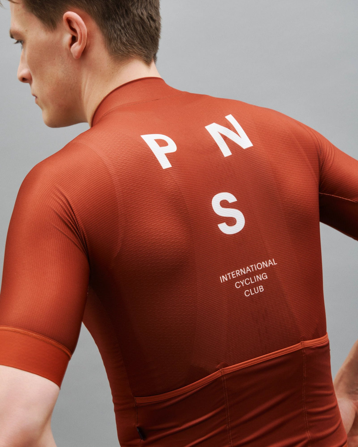 Maillot Corto Pas Normal Studios Mechanism en Brick, vista trasera sobre ciclista #Color_Brick