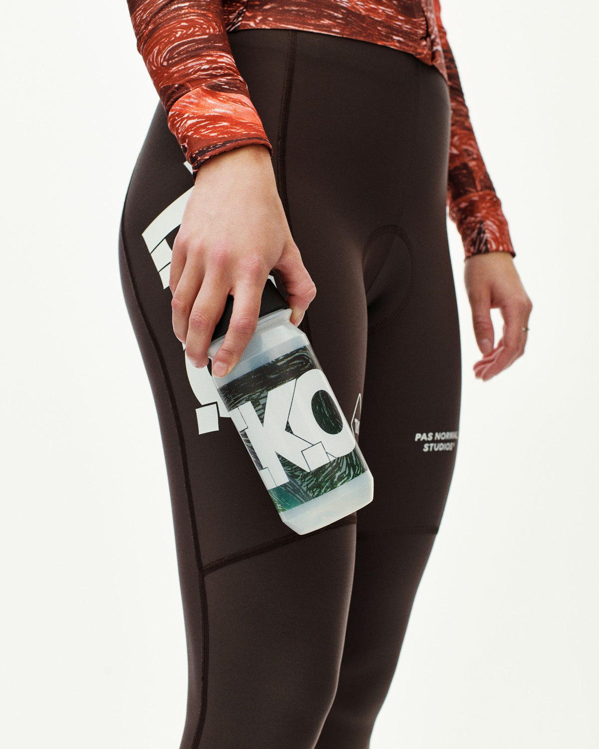 Dark Multi T.K.O. cycling water bottle held by model wearing dark cycling tights, side detail view #Color_T.K.O. Dark Multi