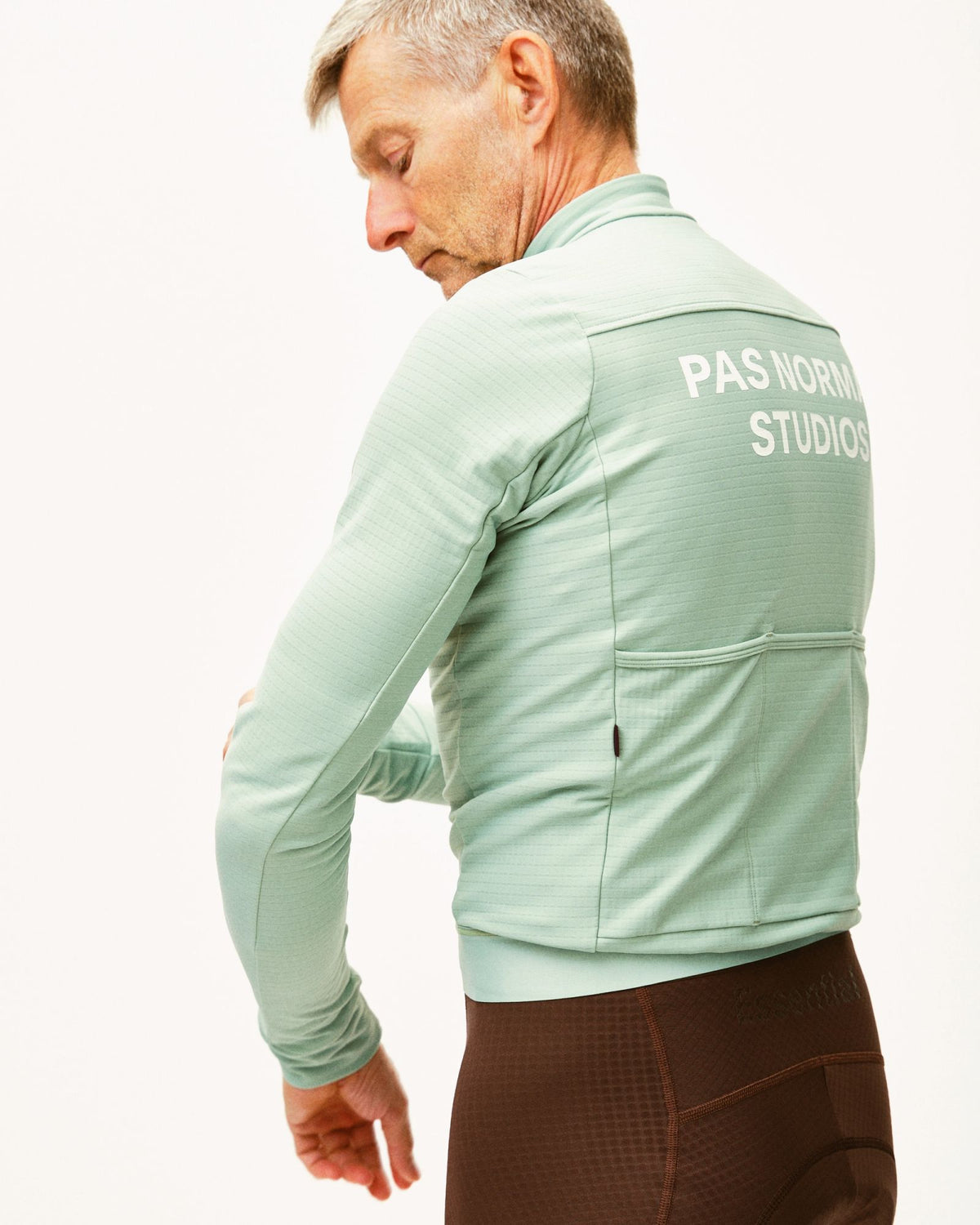 Maillot Largo Pas Normal Studios Essential en Celeste, vista trasera sobre ciclista #Color_Celeste