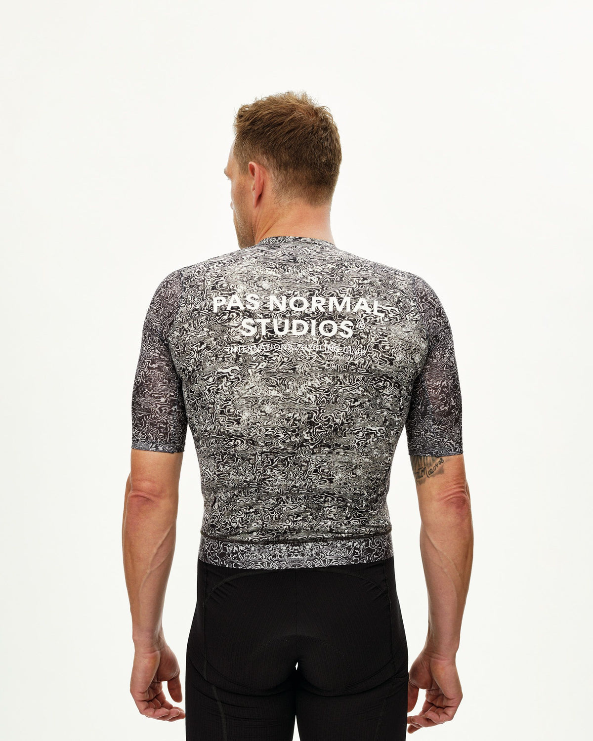 Maillot Corto Pas Normal Studios Essential Light en AOP Grain Off White, vista trasera sobre ciclista #Color_AOP Grain Off White