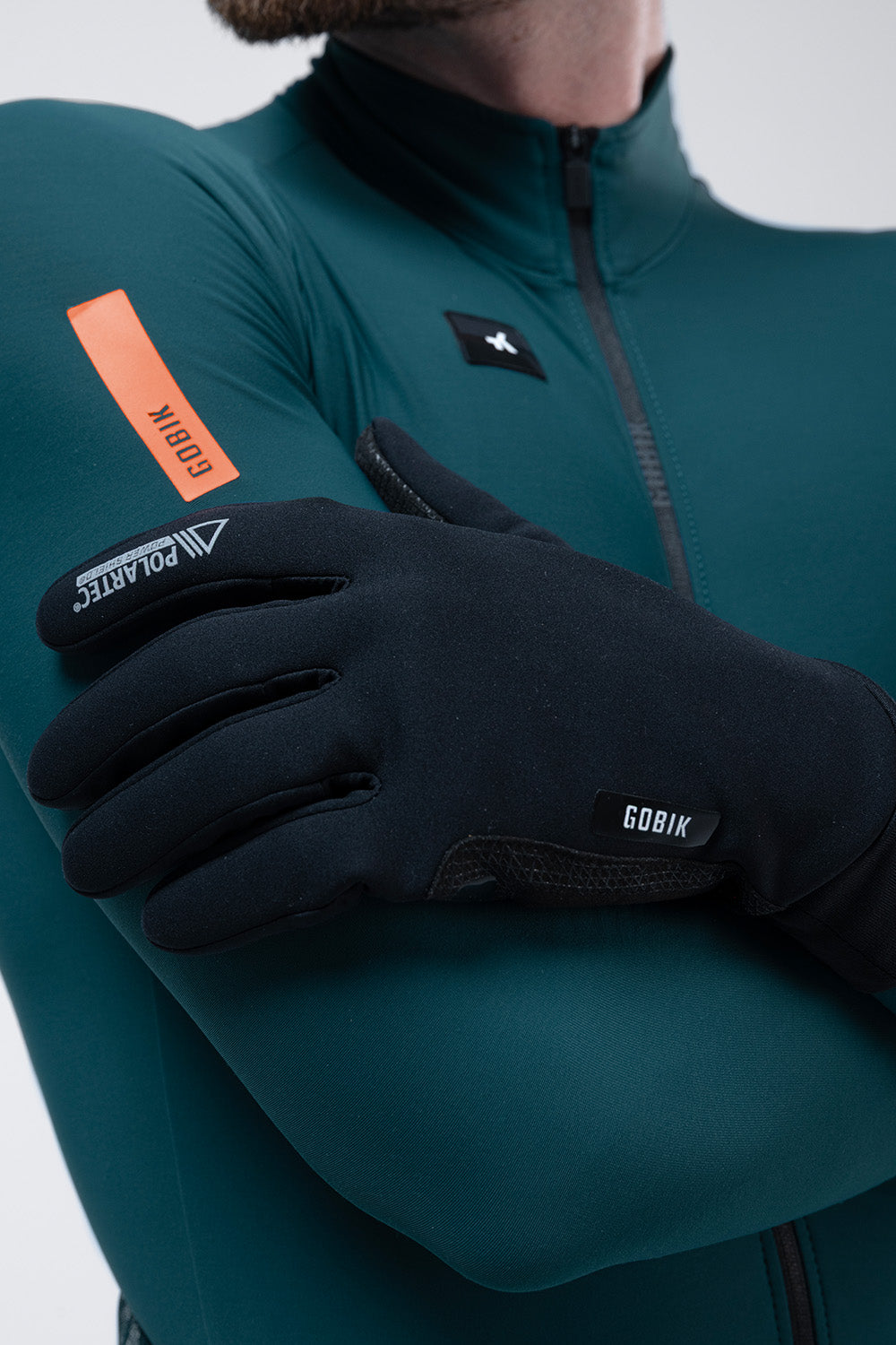 Guantes Gobik Bora 2.0 en True Black, detalle de la mano con el guante puesto sobre el maillot verde #Color_True Black
