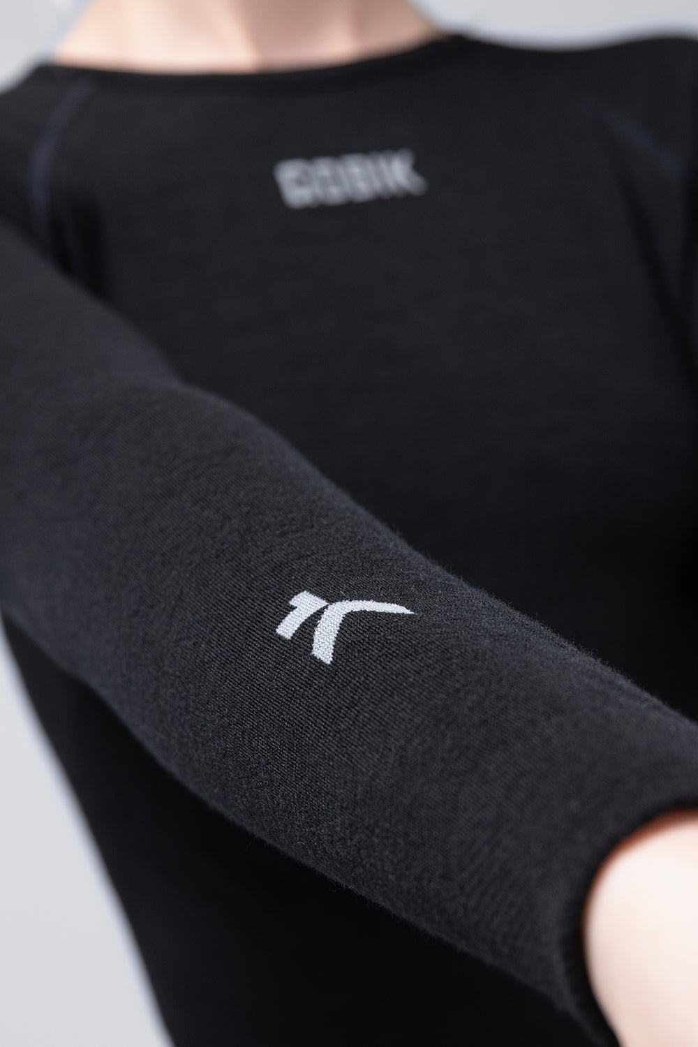 Camiseta Interior Manga Larga Mujer Gobik Winter Merino en Coal, detalle de la manga larga con el logotipo bordado en el antebrazo #Color_Coal