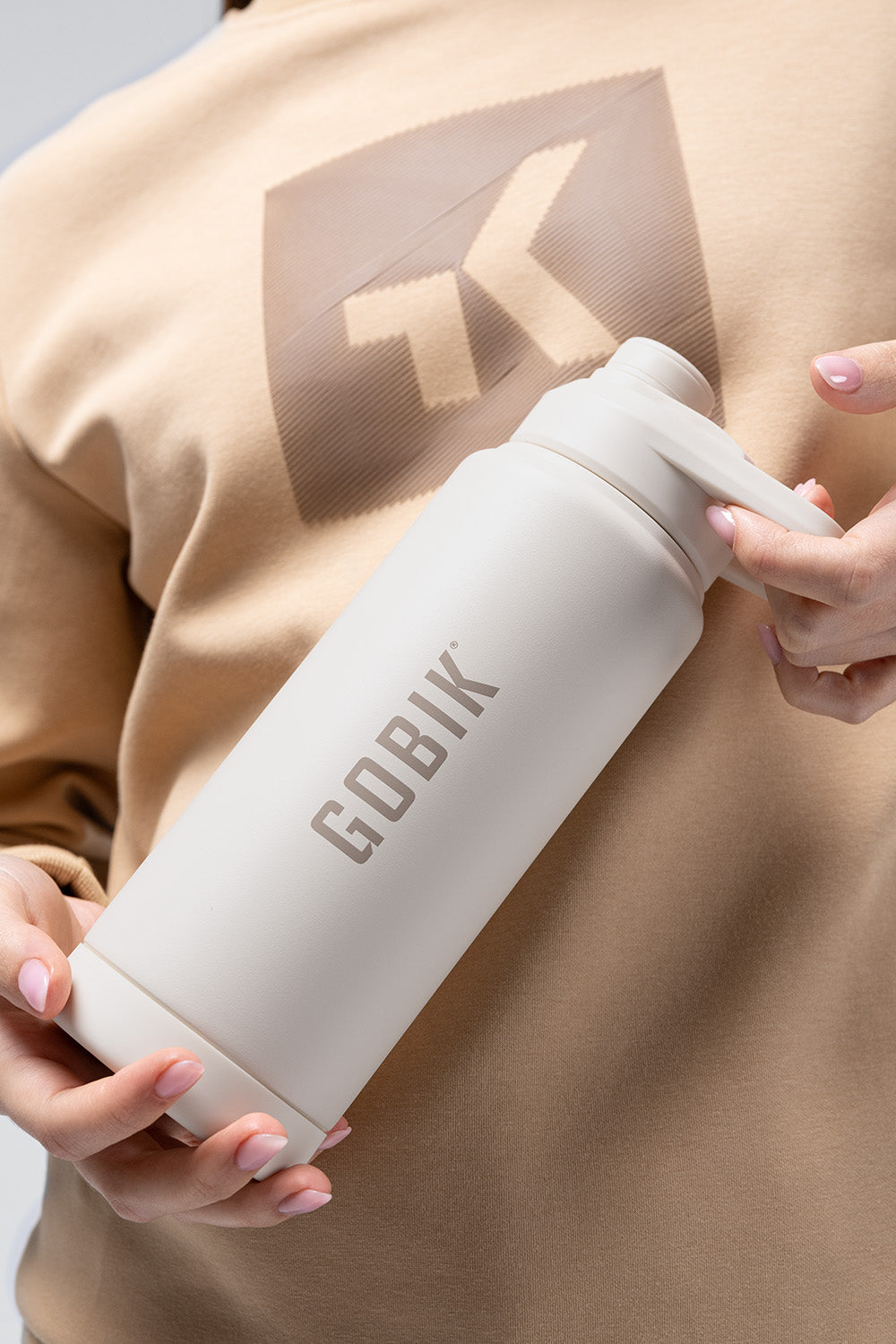 Botella Térmica Gobik Sui en Starlet, persona sujetando la botella crema por el cuerpo #Color_Starlet