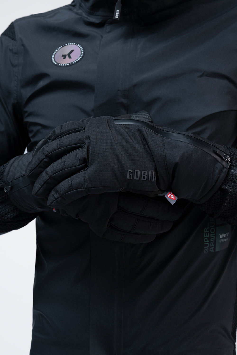 Guantes Gobik Zero 2.0 en True Black, detalle de las manos con los guantes puestos sobre la chaqueta negra #Color_True Black